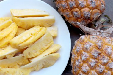 Kesme taze ananas ve ananas Asya tarzı eski ahşap arka plan üzerinde beyaz tabak kabuklu. Tropikal meyve kavramı.