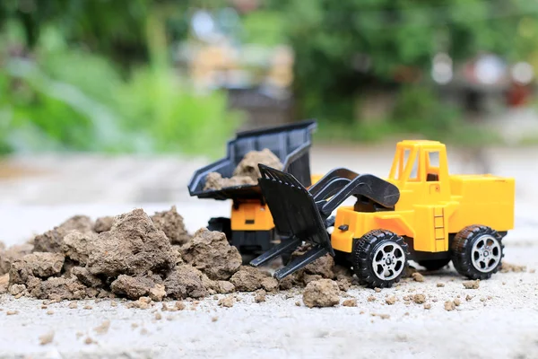 Truck toy car with sand and soil on the concrete floor with blur boken green environment  construction equipment at work ,construction concept, selective focus.