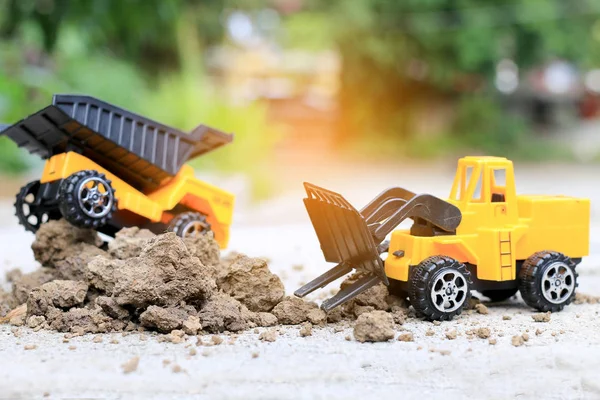 Truck toy car with sand and soil on the concrete floor with blur boken green environment  construction equipment at work ,construction concept, selective focus.