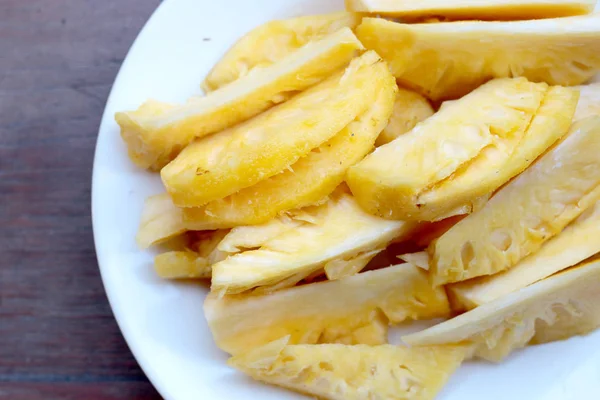 Taze kesme ananas ve ananas kabuklu Asya tarzı eski ahşap arka plan üzerinde beyaz tabak içinde. Tropikal meyve kavramı.
