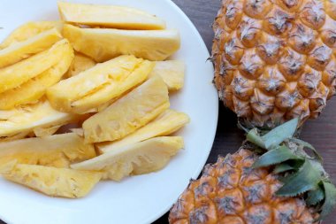 Kesme taze ananas ve ananas Asya tarzı eski ahşap arka plan üzerinde beyaz tabak kabuklu. Tropikal meyve kavramı.