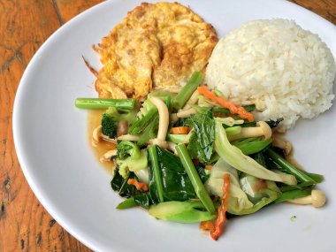 Kızarmış sebze Tay omlet (yumurta) ile pirinç rustik ahşap arka plan üzerinde beyaz plaka ile karıştırın. Vejetaryen yiyecekler, sağlıklı gıda.