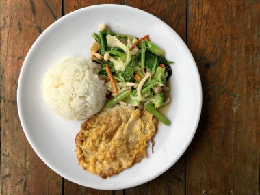 Kızarmış sebze Tay omlet (yumurta) ile pirinç rustik ahşap arka plan üzerinde beyaz plaka ile karıştırın. Vejetaryen yiyecekler, sağlıklı gıda.