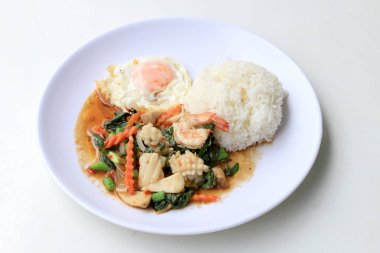 Asya gıda, kızarmış heyecan chili Yapıştır ile deniz ürünleri ve pirinç beyaz tabakta, baharatlı sıcak biber Tayland yemekleri ile fesleğen yaprakları.