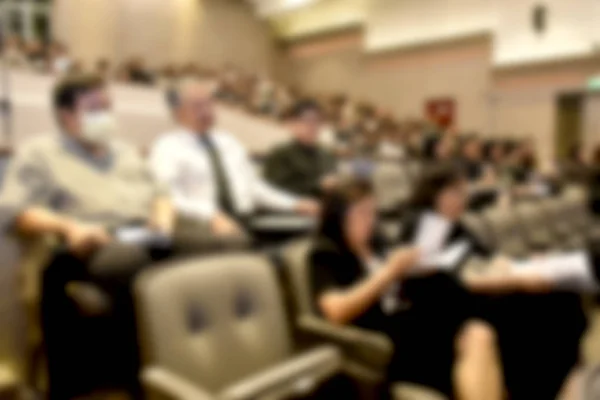 Education concept. Abstract blurred background image of education people, business people and students sitting in conference room or large hall with screen and projector for showing information.