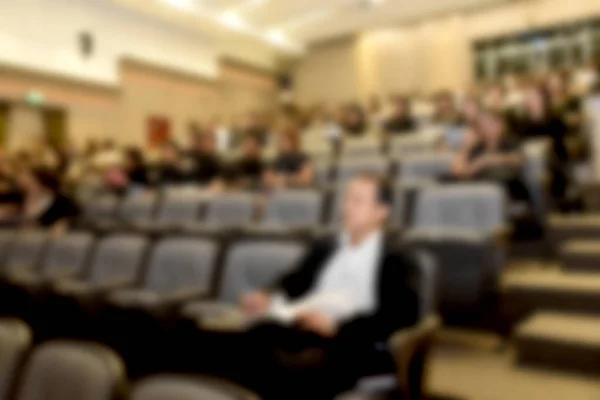 Education concept. Abstract blurred background image of education people, business people and students sitting in conference room or large hall with screen and projector for showing information.