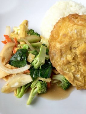 Ahşap arka plan beyaz bir tabağa omlet ile kızartma sebze ilave edin. Tay tarzı yiyecek. Vejetaryen yiyecekler