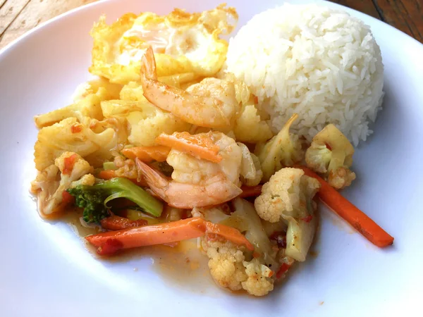 fasulye ve pilav ve kızarmış yumurta ahşap arka plan üzerinde beyaz tabak karides sebzeler ile tavada. Tay tarzında gıda.