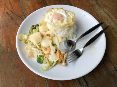 Tofu ve ahşap arka plan üzerinde beyaz tabak pirinç kızarmış yumurta ile tavada kızartılmış karışık sebze. Vejetaryen yiyecekler, sağlıklı gıda.