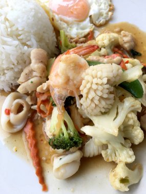 Kızarmış sebze, karnabahar, havuç, pirinç ve ahşap arka plan üzerinde beyaz tabak içinde kızarmış yumurta ile deniz ürünleri ile şeker bezelye karışımı. Tay tarzında gıda.