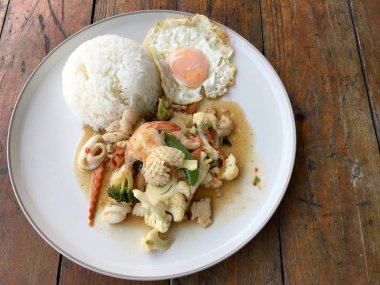 Kızarmış sebze, karnabahar, havuç, pirinç ve ahşap arka plan üzerinde beyaz tabak içinde kızarmış yumurta ile deniz ürünleri ile şeker bezelye karışımı. Tay tarzında gıda.