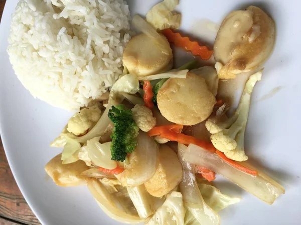 Kızarmış tofu sebze ile Tayland Yasemin pirinç ahşap arka plan üzerinde beyaz tabak ile. Gıda Tay tarzında. Vejetaryen yiyecekler.