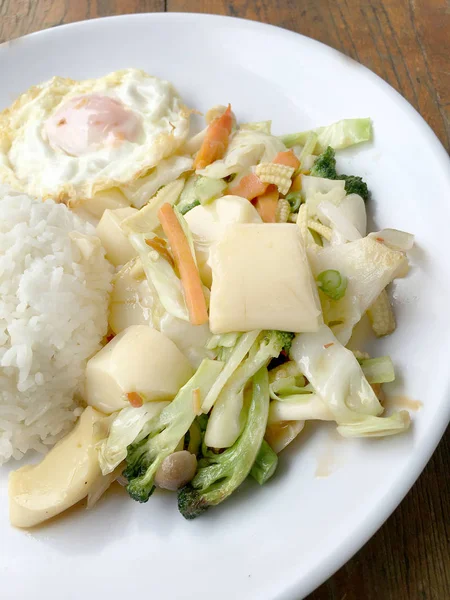 Tofu ve ahşap arka plan üzerinde beyaz tabak pirinç kızarmış yumurta ile tavada kızartılmış karışık sebze. Vejetaryen yiyecekler, sağlıklı gıda.
