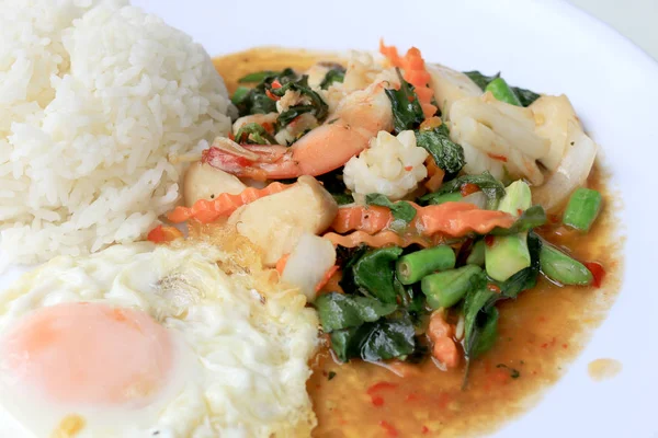 Asya gıda, kızarmış heyecan chili Yapıştır ile deniz ürünleri ve pirinç beyaz tabakta, baharatlı sıcak biber Tayland yemekleri ile fesleğen yaprakları.