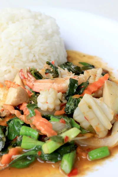 Asya gıda, kızarmış heyecan chili Yapıştır ile deniz ürünleri ve pirinç beyaz tabakta, baharatlı sıcak biber Tayland yemekleri ile fesleğen yaprakları.