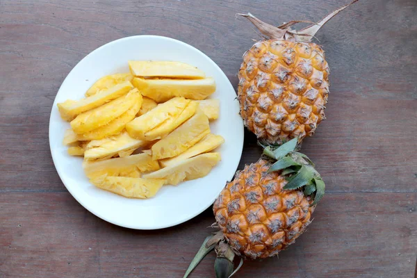 Taze kesme ananas ve ananas kabuklu Asya tarzı eski ahşap arka plan üzerinde beyaz tabak içinde. Tropikal meyve kavramı.
