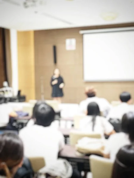 Education concept, Abstract blurred background image of students and business people  studying and discuss in large hall profession seminar with screen and projector for showing information.