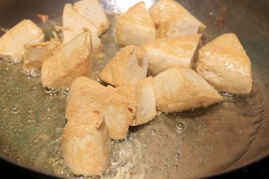 Pişirme tofu kızartma yağı, soya peyniri kızartma adet özel bir ızgarada pişirme süreci mutfakta pan. Vejetaryen yemekleri. Soya soya peyniri ızgara. Kızarmış Tofu tarifi, yumuşak odak.