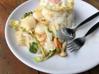 Tofu ve ahşap arka plan üzerinde beyaz tabak pirinç kızarmış yumurta ile tavada kızartılmış karışık sebze. Vejetaryen yiyecekler, sağlıklı gıda.