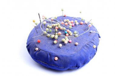 Mavi el yapımı yastık üzerinde izole beyaz arka planda kalmış çok renkli dikiş iğne ile hissettim.