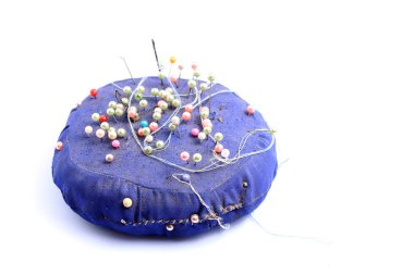 Mavi el yapımı yastık üzerinde izole beyaz arka planda kalmış çok renkli dikiş iğne ile hissettim.