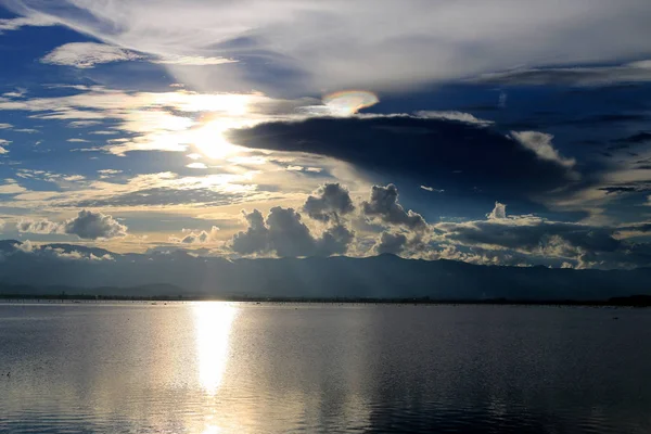 Güzel gün batımı ve dağ ve bulutlar ve Günbatımı ile akşam gökyüzü arka plan için göle yansıyan. Kırsal manzara renkli gökyüzü gün batımında altında şafak Sunrise.