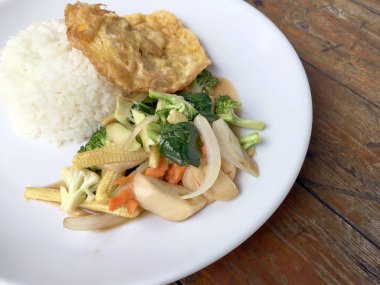 Ahşap arka plan beyaz bir tabağa omlet ile kızartma sebze ilave edin. Tay tarzı yiyecek. Vejetaryen yiyecekler