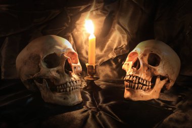 Kafatası pranga ve doku ile siyah kumaş üzerine mum mum loş ışık gece ışık ile natürmort. mum gece zamanında ışık görüntü sesi.