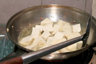 Pişirme tofu kızartma yağı, soya peyniri kızartma adet özel bir ızgarada pişirme süreci mutfakta pan. Vejetaryen yemekleri. Soya soya peyniri ızgara. Kızarmış Tofu tarifi, yumuşak odak.