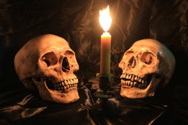 Kafatası pranga ve doku ile siyah kumaş üzerine mum mum loş ışık gece ışık ile natürmort. mum gece zamanında ışık görüntü sesi.