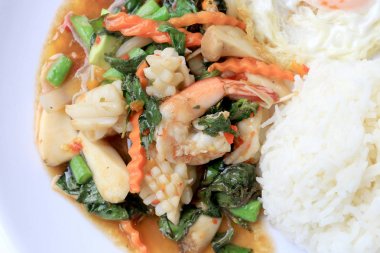 Asya gıda, kızarmış heyecan chili Yapıştır ile deniz ürünleri ve pirinç beyaz tabakta, baharatlı sıcak biber Tayland yemekleri ile fesleğen yaprakları.