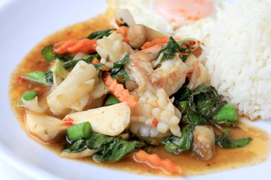 Asya gıda, kızarmış heyecan chili Yapıştır ile deniz ürünleri ve pirinç beyaz tabakta, baharatlı sıcak biber Tayland yemekleri ile fesleğen yaprakları.