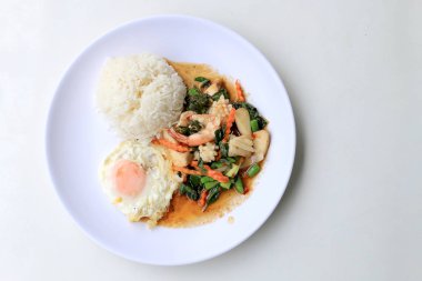 Asya gıda, kızarmış heyecan chili Yapıştır ile deniz ürünleri ve pirinç beyaz tabakta, baharatlı sıcak biber Tayland yemekleri ile fesleğen yaprakları.