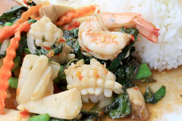 Asya gıda, kızarmış heyecan chili Yapıştır ile deniz ürünleri ve pirinç beyaz tabakta, baharatlı sıcak biber Tayland yemekleri ile fesleğen yaprakları.