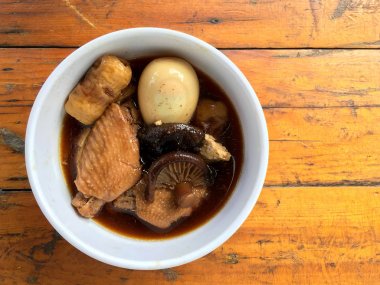 Herb, yumurta ve kanat komposto domuz eti tavuk soya sosu veya tatlı kahverengi sos (Moo Pa-lo) içinde ahşap masa, Tay geleneksel gıda üzerinde beyaz darbe.