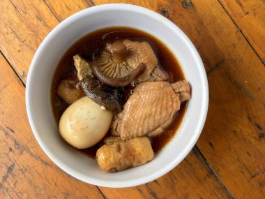 Herb, yumurta ve kanat komposto domuz eti tavuk soya sosu veya tatlı kahverengi sos (Moo Pa-lo) içinde ahşap masa, Tay geleneksel gıda üzerinde beyaz darbe.