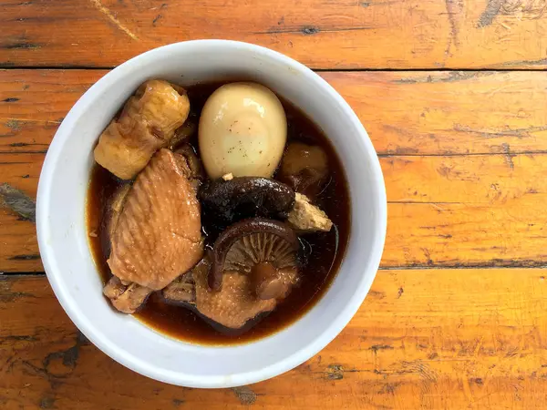 Herb, yumurta ve kanat komposto domuz eti tavuk soya sosu veya tatlı kahverengi sos (Moo Pa-lo) içinde ahşap masa, Tay geleneksel gıda üzerinde beyaz darbe.