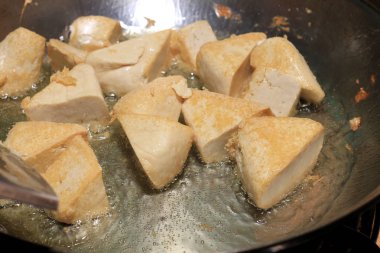 Pişirme tofu kızartma yağı, soya peyniri kızartma adet özel bir ızgarada pişirme süreci mutfakta pan. Vejetaryen yemekleri. Soya soya peyniri ızgara. Kızarmış Tofu tarifi, yumuşak odak.