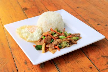 Lezzetli Tay tavuk pilav ile beyaz tabak içinde karıştırın kızarmış sebze ile çanak ve ahşap masa üstünde yumurta kızarmış. Tayland gıda.