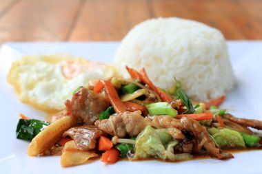 Lezzetli Tay tavuk pilav ile beyaz tabak içinde karıştırın kızarmış sebze ile çanak ve ahşap masa üstünde yumurta kızarmış. Tayland gıda.