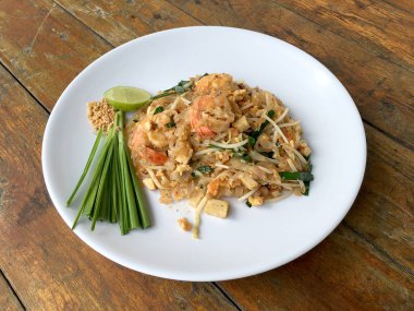 Yastık tavada kızartılmış Tay, Pirinç Noodle ile ahşap masa üzerinde beyaz tabak karides. Tayland'ın ulusal ana yemek biri. Tayland popüler gıda. Tayland kızarmış noodle