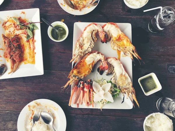 Delicioso Grilled Giant River Prawn con trozos de chile y perejil en plato blanco con salsa de soja en un tazón pequeño en el centro, en la mesa de madera en el restaurante, vista desde arriba. Comida estilo tailandés. tono vintage — Foto de Stock