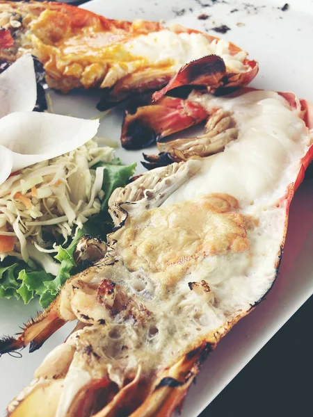 Heerlijke gegrilde Giant River garnaal met stukken van Spaanse peper en peterselie op witte schotel met sojasaus in kommetje in centrum, op houten tafel in restaurant, bekijken van bovenaf. Thaise stijl voedsel. Vintage Toon — Stockfoto