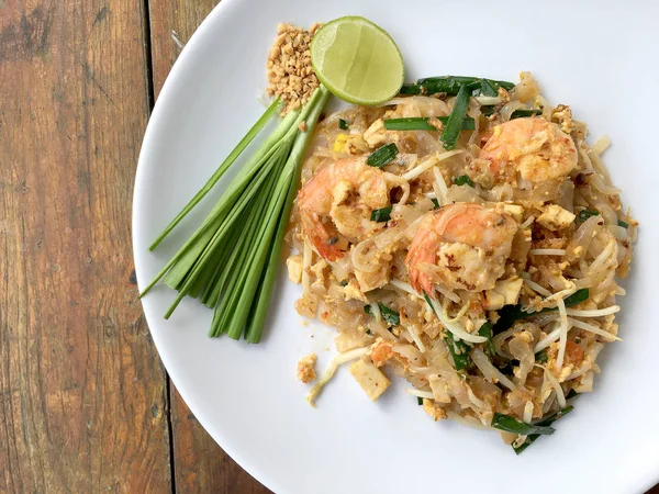 Pad Thai, geroerbakt rijst noedels met garnalen in witte plaat op houten tafel. Één van Thailand's nationale hoofdgerecht. de populaire eten in Thailand. Thaise noedels — Stockfoto