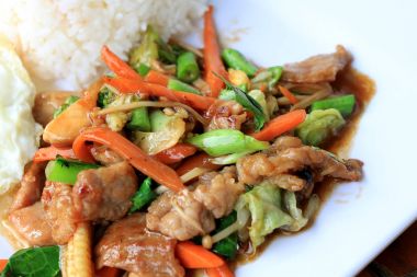 Lezzetli Tay tavuk pilav ile beyaz tabak içinde karıştırın kızarmış sebze ile çanak ve ahşap masa üstünde yumurta kızarmış. Tayland gıda.