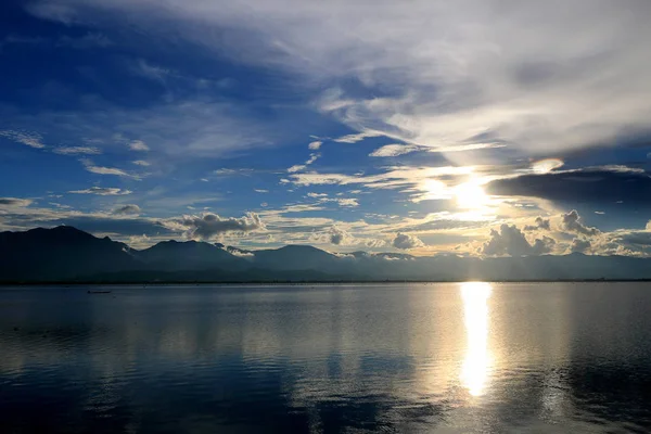 Belo pôr-do-sol e céu noturno com montanha e nuvens e pôr-do-sol refletido no lago para fundo. Paisagem do campo sob o céu colorido cênico no nascer do sol do amanhecer . — Fotografia de Stock