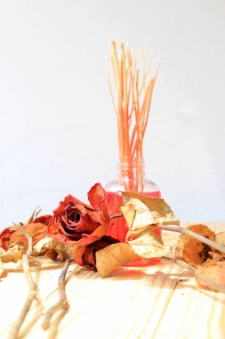 El yapımı pf koku difüzör ayarla: şişe aroma sopalarla ve kuru kırmızı gül (reed difüzör), çam ahşap masa duvar arka plan ile parfüm sprey şişeyle.