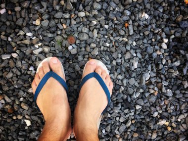 Taş plajda bir adamın ayakları