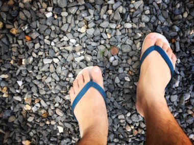 Taş plajda bir adamın ayakları