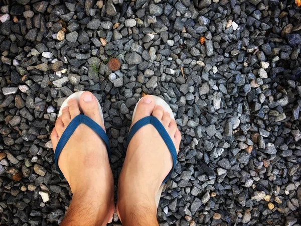 Taş plajda bir adamın ayakları